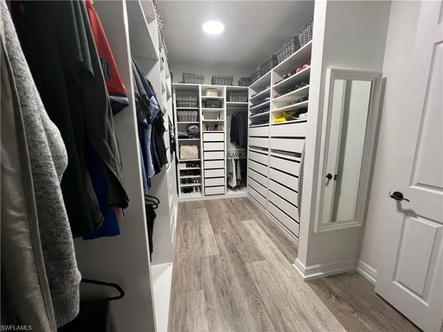 Walk in closet with wood-type flooring