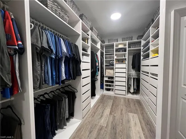 Walk in closet with wood-type flooring