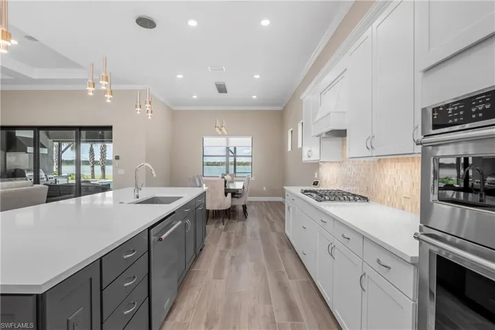 Open Kitchen/Dining room featuring appliances with stainless steel finishes, white cabinets, hanging light fixtures, and light hardwood / wood-style floors