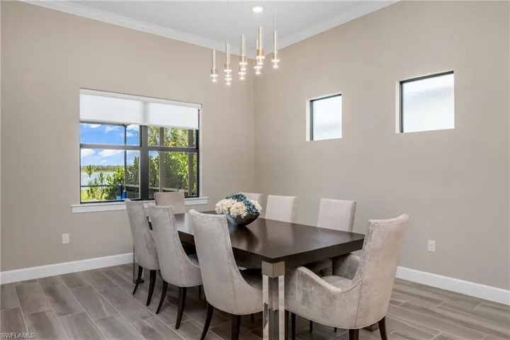 Dining room with ornamental molding, light hardwood / wood-style flooring, designer lighting and beautiful lake views.