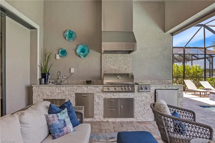 Custom outdoor kitchen includes natural gas grill, double side burners, beverage cooler, sink, garbage drawer, and under counter storage space.
