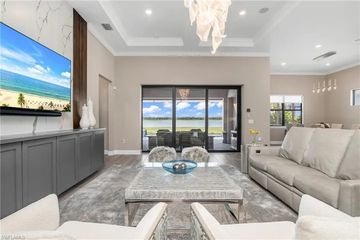 Family room features tray ceilings with decorative crown molding, designer lighting, custom feature wall with tile, lighting, detailed cabinetry and storage drawers.