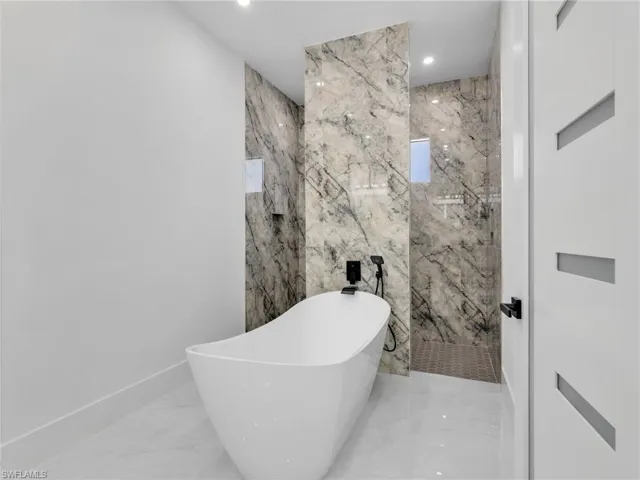 Bathroom with a freestanding tub, light marble finish flooring, stone wall, recessed lighting, and a marble finish shower