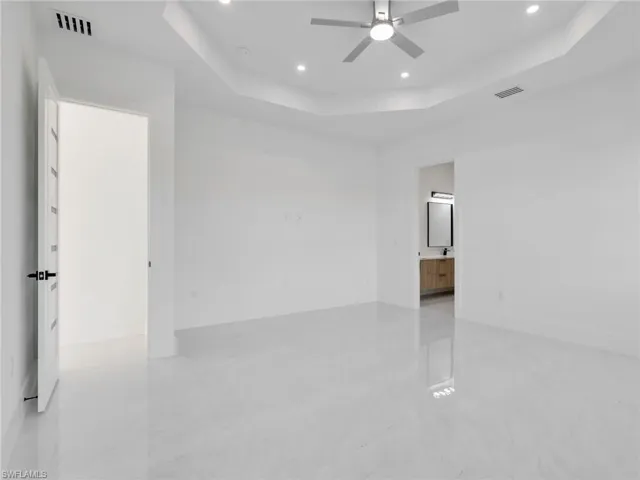 Empty room with ceiling fan, a raised ceiling, and recessed lighting