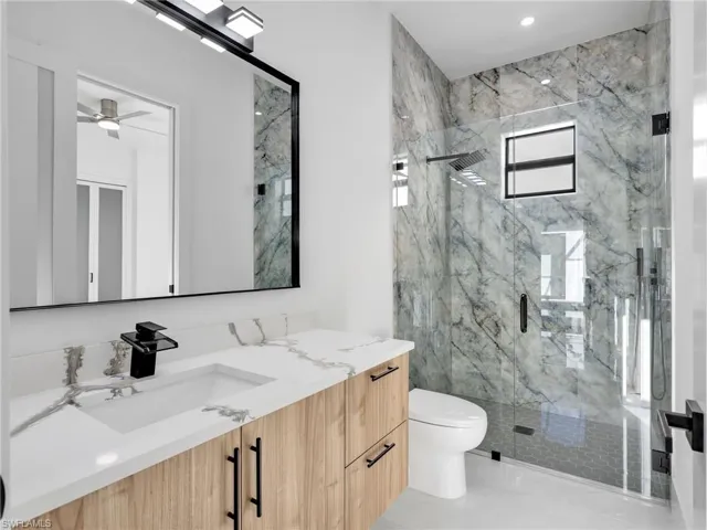 Bathroom with vanity and a marble finish shower