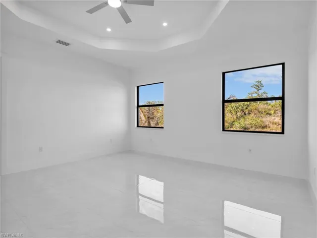Unfurnished room with a raised ceiling, ceiling fan, and recessed lighting