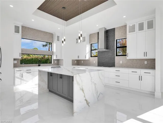 Kitchen with plenty of natural light, light stone countertops, and glass fronted cabinets