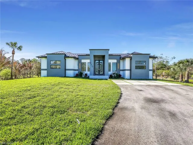 Contemporary house featuring a front yard, stucco siding, asphalt driveway, and a standing seam roof