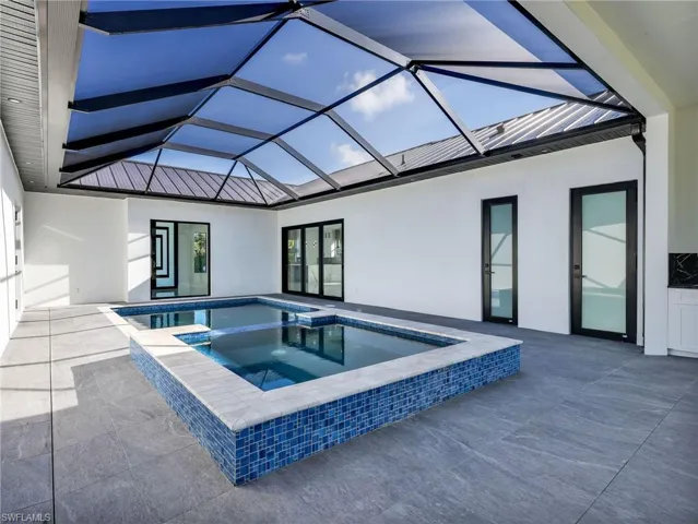 Integrated pool / spa featuring a sunroom, a patio, and glass enclosure