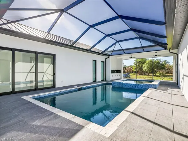 Integrated pool / spa with a sunroom, glass enclosure, and a patio