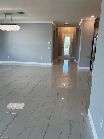 Entrance foyer with suspended lighting, crown molding, and light marble finish flooring