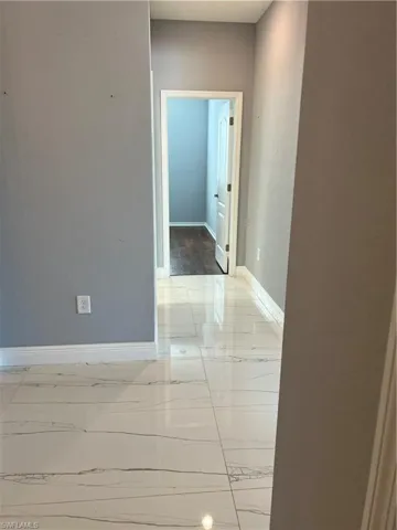 Corridor featuring baseboards and a textured wall