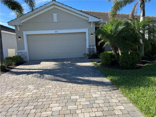 Ranch-style home with decorative driveway, stucco siding, a tile roof, a garage, and stone siding
