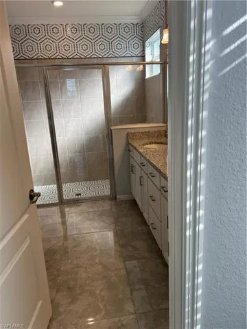 Bathroom with vanity, a stall shower, and crown molding