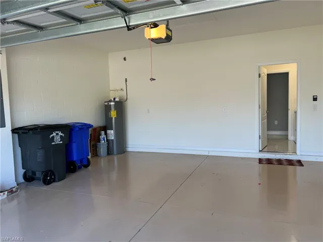 Garage with concrete block wall, electric water heater, and a garage door opener