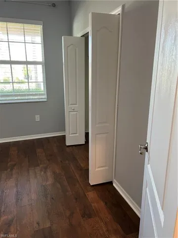 Unfurnished bedroom featuring dark wood-style flooring and baseboards