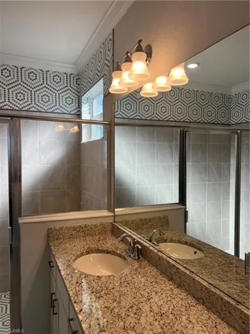 Bathroom featuring ornamental molding, vanity, a shower stall, and tile walls