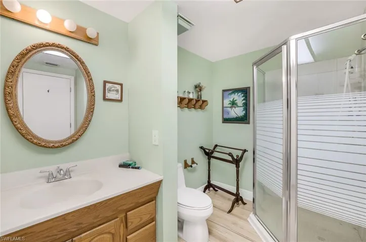 Bathroom featuring hardwood / wood-style flooring, an enclosed shower, vanity, and toilet