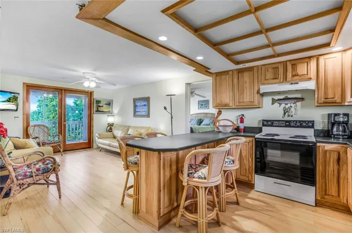 Kitchen with a kitchen bar, electric stove, light wood-type flooring, kitchen peninsula, and ceiling fan
