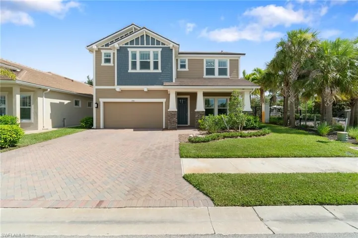 Craftsman-style home with decorative driveway, stone siding, and an attached garage