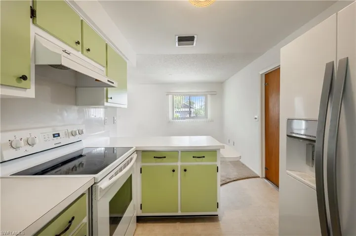 Kitchen with electric stove, fridge with ice dispenser, and green cabinets