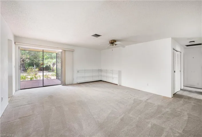 Empty room featuring a textured ceiling, carpet floors, and a ceiling fan