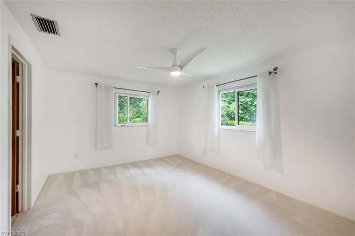 Spare room featuring plenty of natural light, carpet flooring, a textured ceiling, and ceiling fan