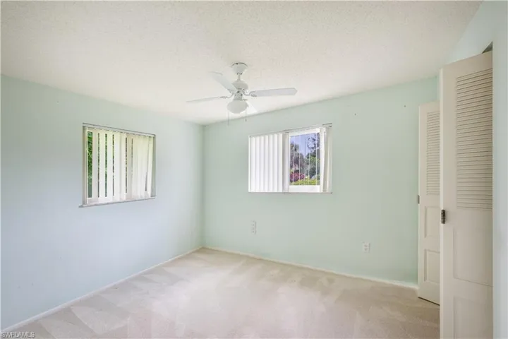 Unfurnished bedroom with light colored carpet, ceiling fan, a textured ceiling, and a closet