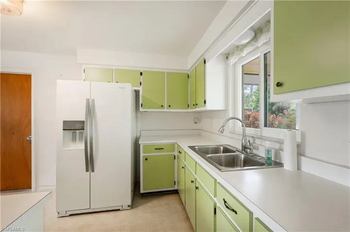 Kitchen with white fridge with ice dispenser, light countertops, and green cabinets