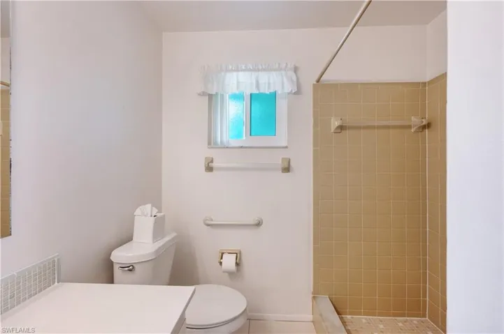 Bathroom featuring vanity, tiled shower, and tile patterned floors