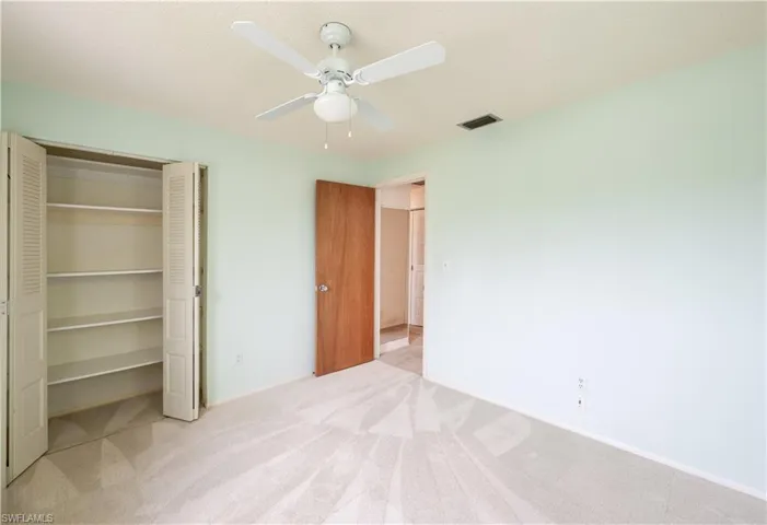 Unfurnished bedroom featuring light carpet, a closet, and ceiling fan