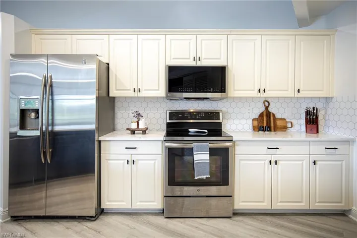 Kitchen with appliances with stainless steel finishes, light stone counters, and decorative backsplash