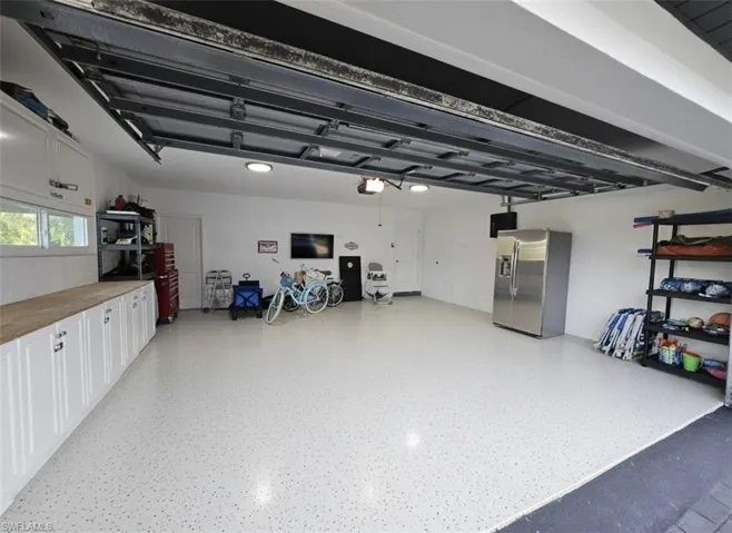 Garage featuring storage shelves for beach gear, cabinets for tools