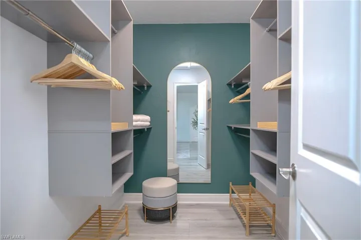 Spacious primary bedroom walk-in closet with arched tall mirror