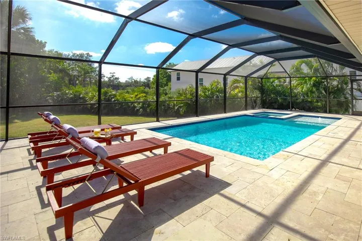 View of screened swimming pool featuring a lanai, a pool with connected hot tub, a patio area