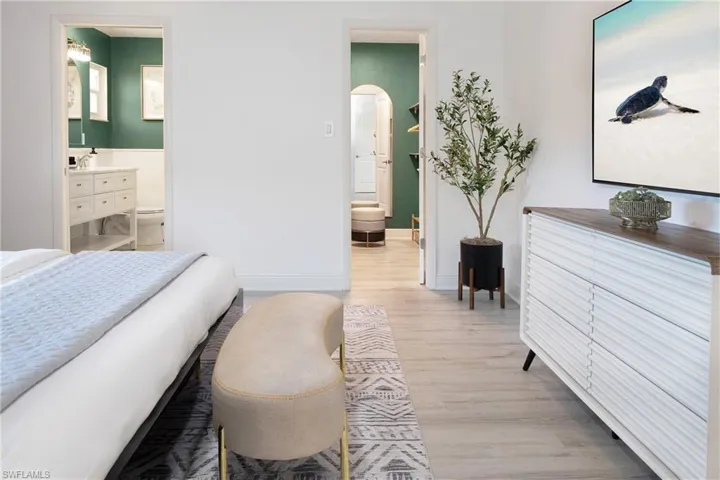 Primary bedroom with an ottoman, dresser, bathroom and walk-in closet views