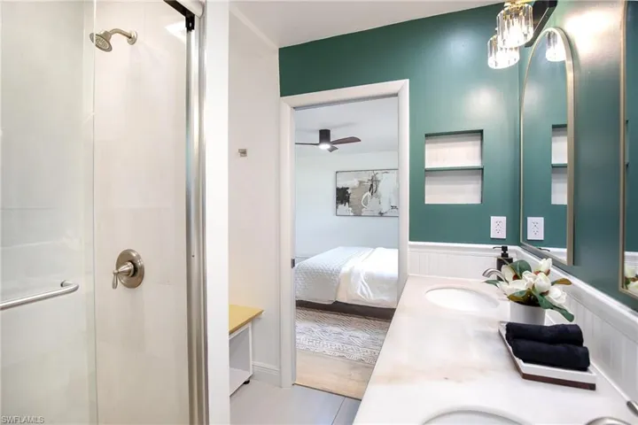 Full primary bathroom featuring double vanity, a shower stall with a primary bedroom view