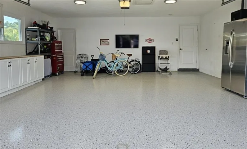 Garage with stainless steel refrigerator with ice dispenser and a garage door opener