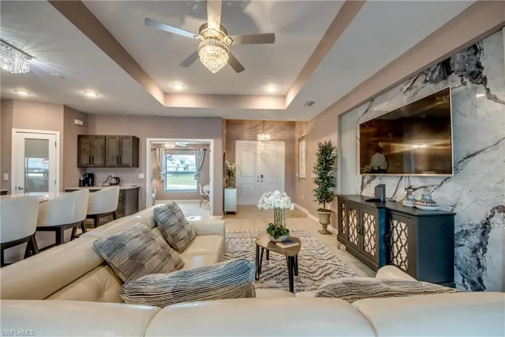 Living area featuring a raised ceiling, a ceiling fan, and recessed lighting