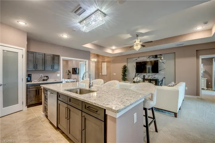 Kitchen with appliances with stainless steel finishes, open floor plan, a center island with sink, a kitchen breakfast bar, and a tray ceiling