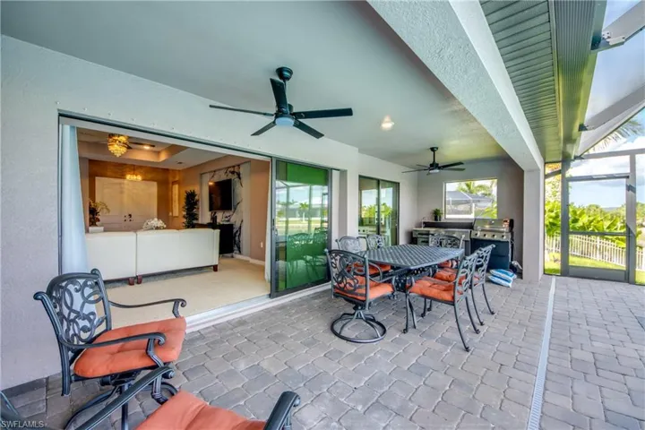 View of patio / terrace with ceiling fan, glass enclosure, outdoor dining space, and area for grilling