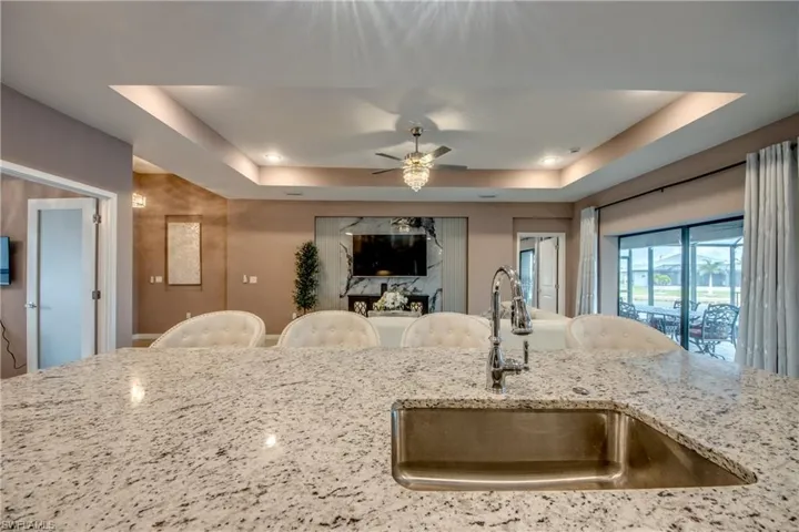 Kitchen with appliances with stainless steel finishes, a kitchen bar, an island with sink, light stone counters, and recessed lighting