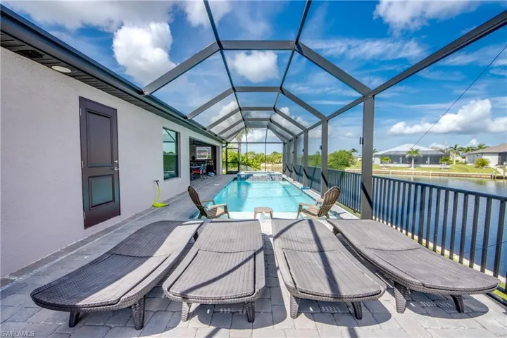 View of pool with a patio, a pool with connected hot tub, a lanai, and a water view