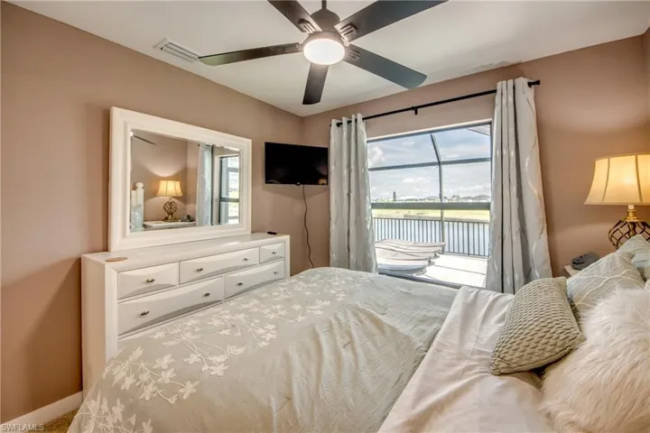 Bedroom with access to exterior, a raised ceiling, recessed lighting, light carpet, and ceiling fan
