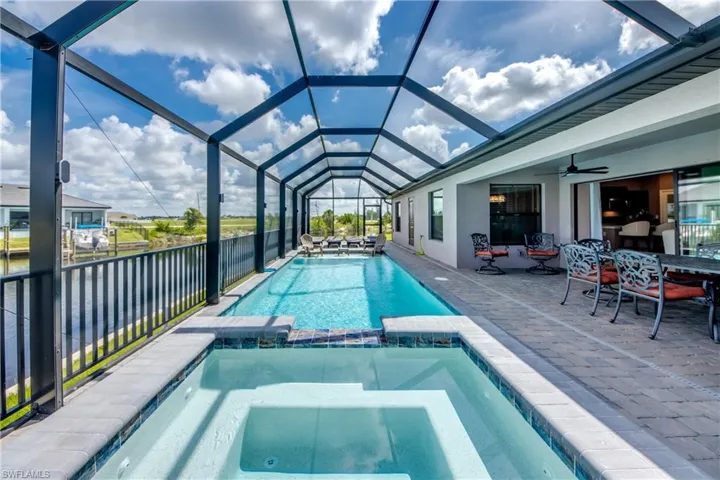 View of swimming pool featuring a pool with connected hot tub, a patio, ceiling fan, a lanai, and outdoor dining area