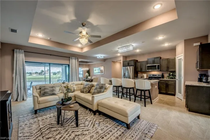 Living area featuring a tray ceiling, light carpet, ceiling fan, and recessed lighting