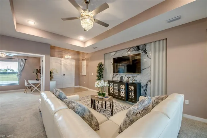 Carpeted living area with a tray ceiling, a ceiling fan, and recessed lighting
