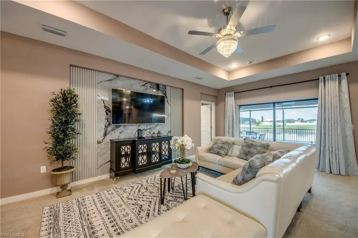 Living area with carpet floors, a raised ceiling, ceiling fan, and recessed lighting
