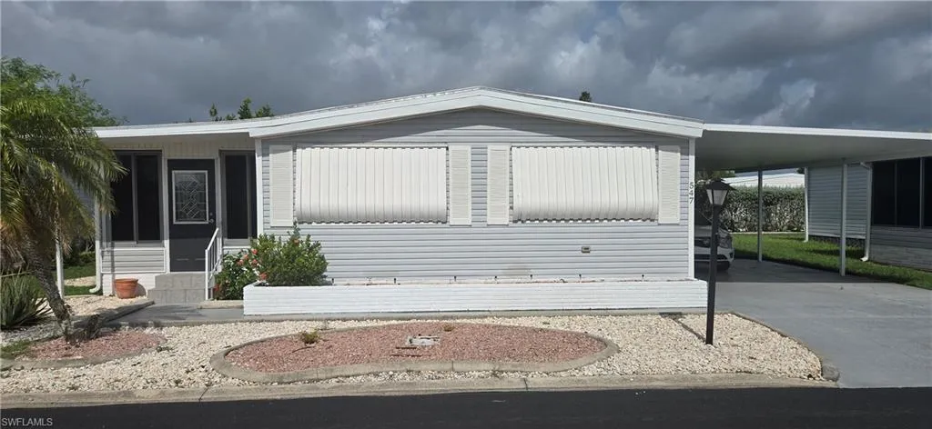Exterior featuring light gray siding, white trim, and a covered carport