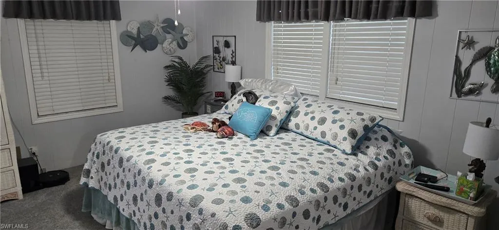 Carpeted bedroom featuring two windows with horizontal blinds and valances